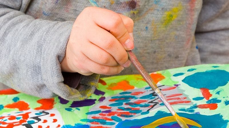 Kinderhand malt mit Pinsel