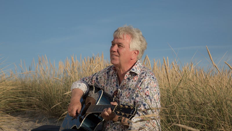 Rolf Zuckowski mit Gitarre am Strand